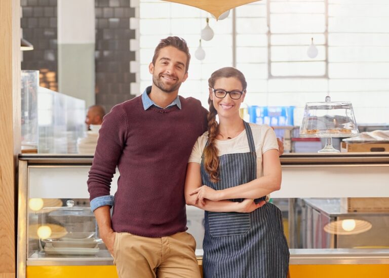 Portrait of two young business owners posing in front of the counter in their coffee shop