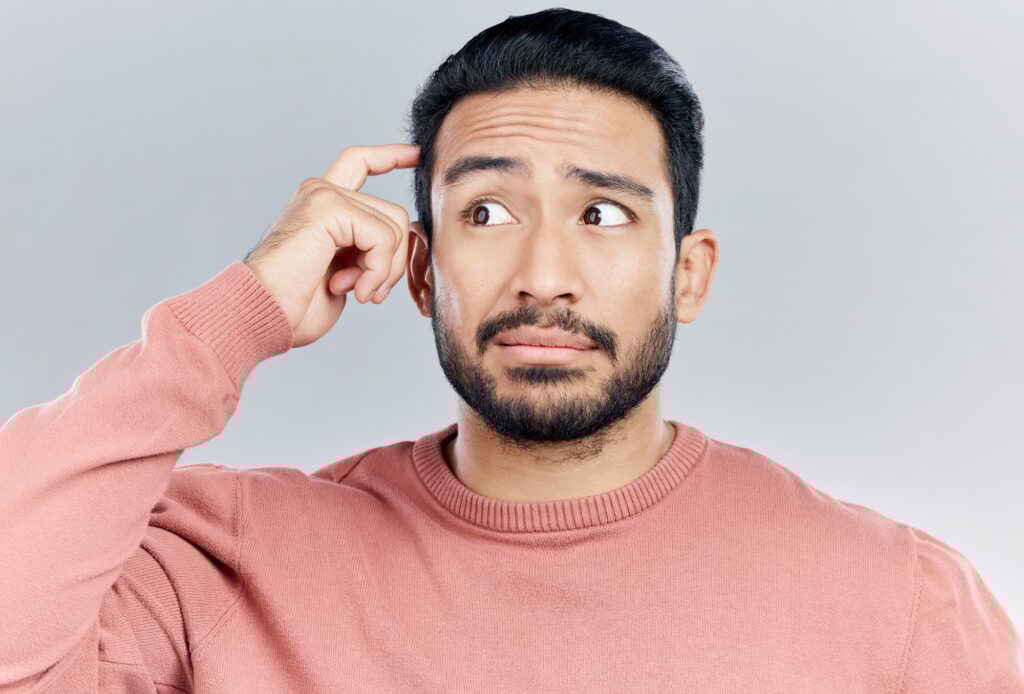 Thinking, question and doubt with a man in studio on a gray background looking thoughtful or contem